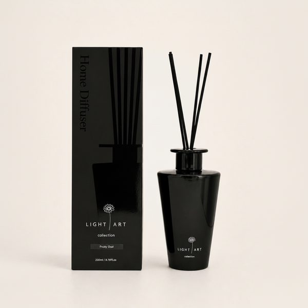 A reed diffuser bottle with black reeds next to its black packaging box, both featuring the brand name 'Light Art' and the scent 'Fruity Oud', on a light beige background.