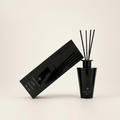 A black reed diffuser bottle with several black reeds standing upright, shown next to its matching black rectangular box on a clean off-white background. The box and bottle are branded Light Art.